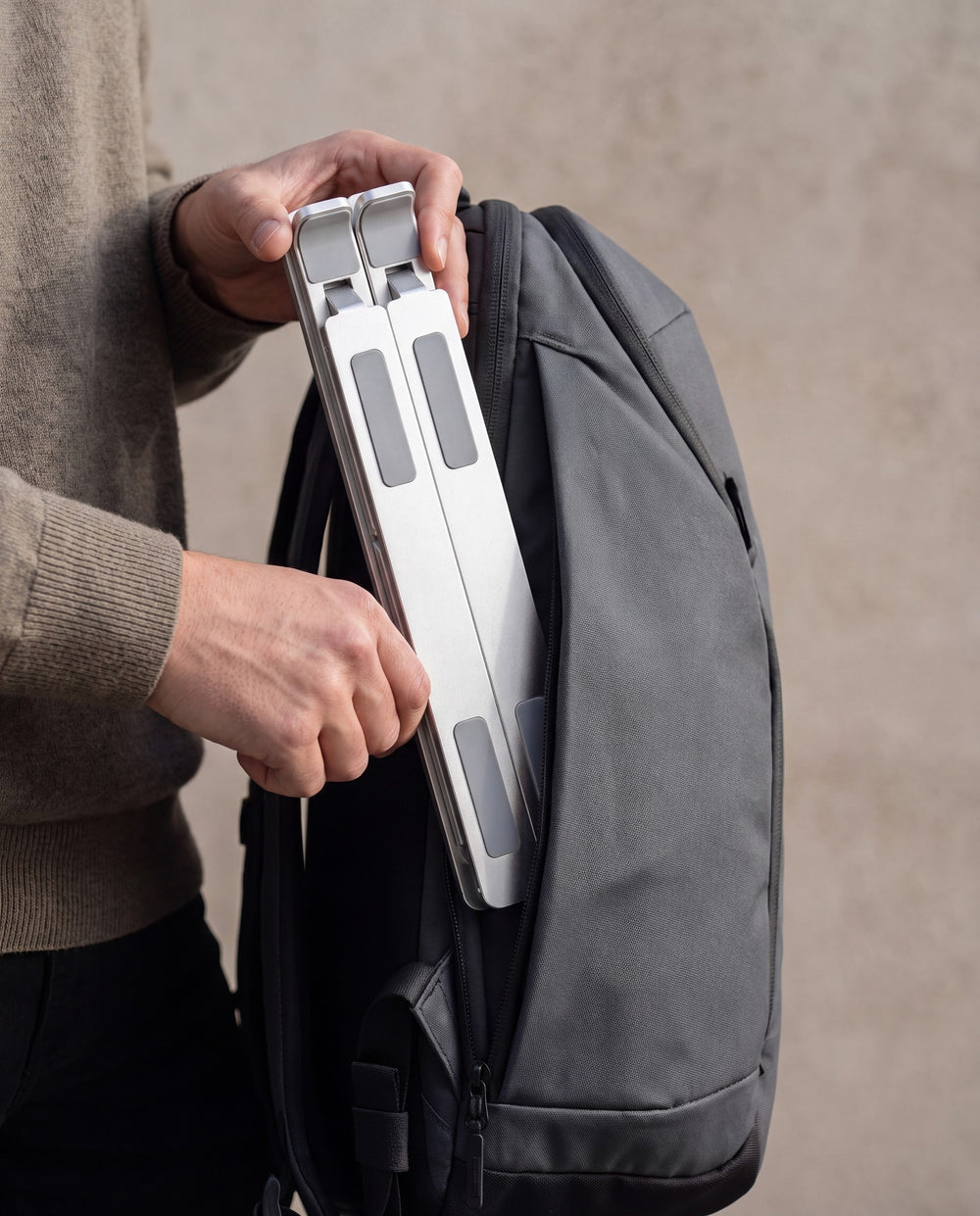 The Riser laptop stand sliding into a laptop bag